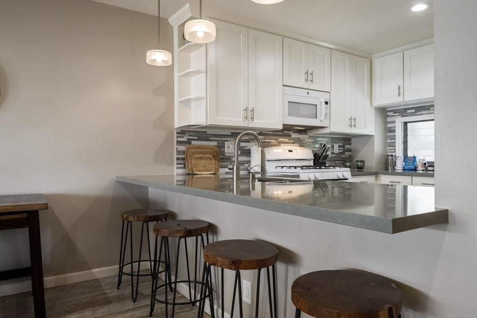 4 stylish bar stools are up against the other side of this modern granite kitchen counter. It's the perfect perch for conversation while someone's in the kitchen cooking.