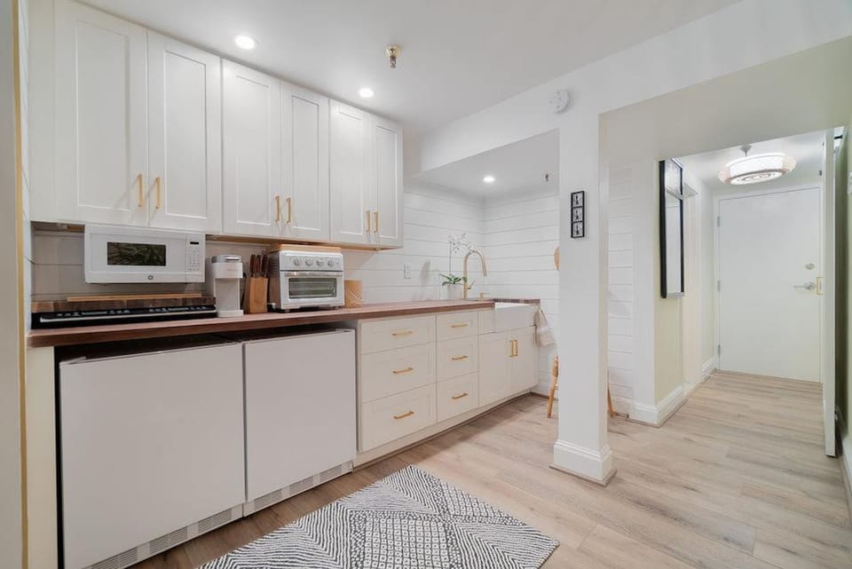 Kitchenette with a Toaster oven, convection cooktop, microwave, 2 mini fridges, Keurig coffee maker, glasses, plates, and cutlery.