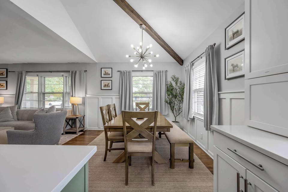 Bright and airy dining space for six, featuring large windows and an open kitchen layout and living room, perfect for shared meals and lively conversation.