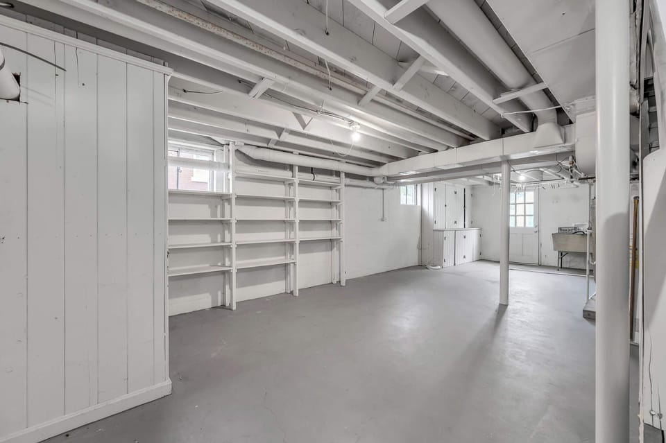 Clean and spacious basement area with built-in shelving and storage, offering plenty of room for organization or extra space during your stay.