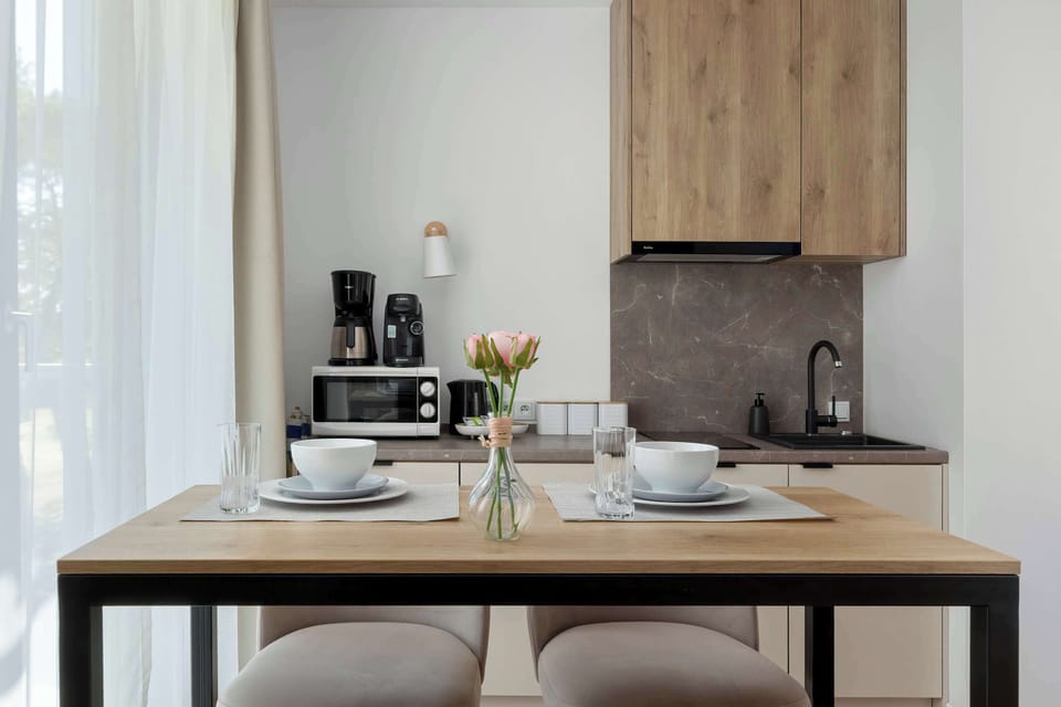 A close-up focuses on a small dining table with two chairs placed beside the kitchen area. Minimal décor keeps the space uncluttered.