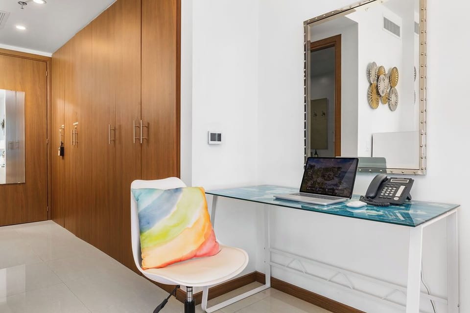 A modern workspace with glass desk, ample storage, and sleek wood wardrobes keeps your stay organized and comfortable.
