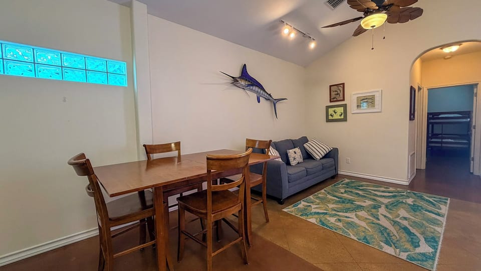 Gather around the warm wood dining table or relax on your cozy sofa in this bright, coastal-themed living space.