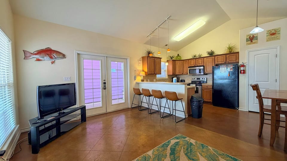 Relax in your open-concept living space where coastal charm meets modern comfort, featuring a full kitchen and entertainment area for memorable vacation moments.