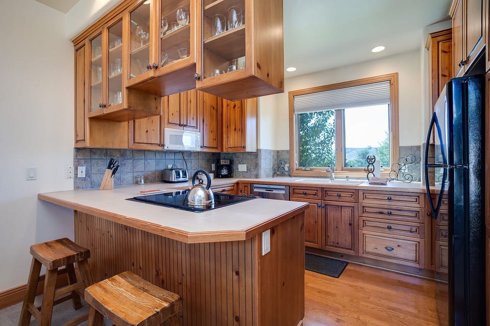 Your fully equipped kitchen features warm wood cabinetry, modern appliances, and a cozy island where you can prepare meals while enjoying scenic views.