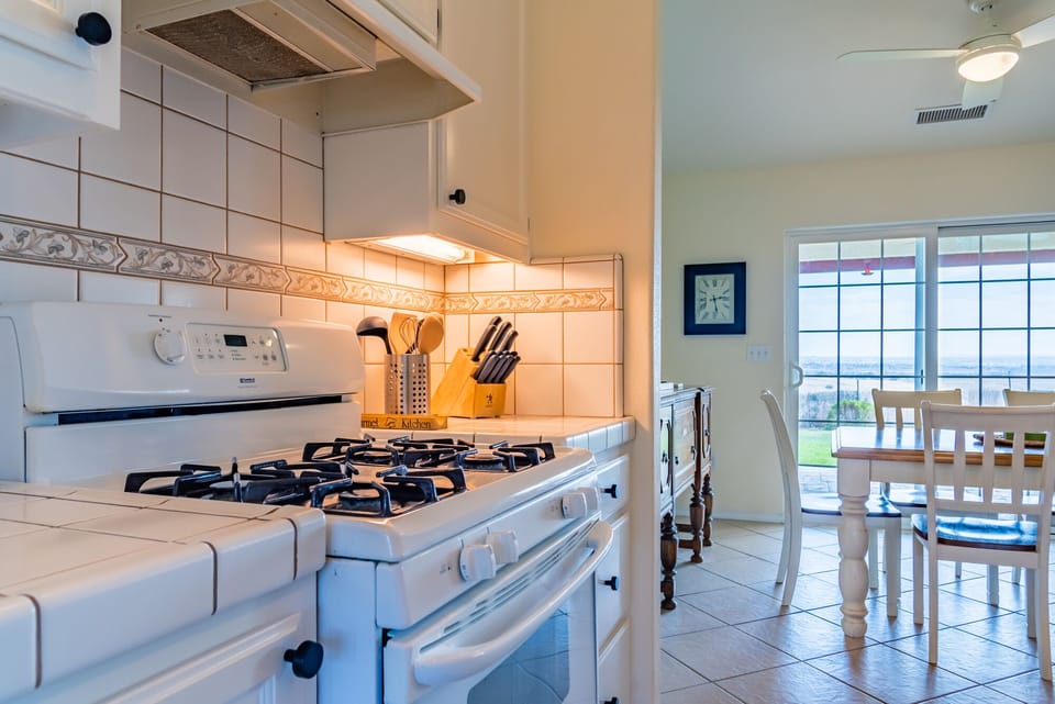 The gas stove sits beside the dining area and bright windows.