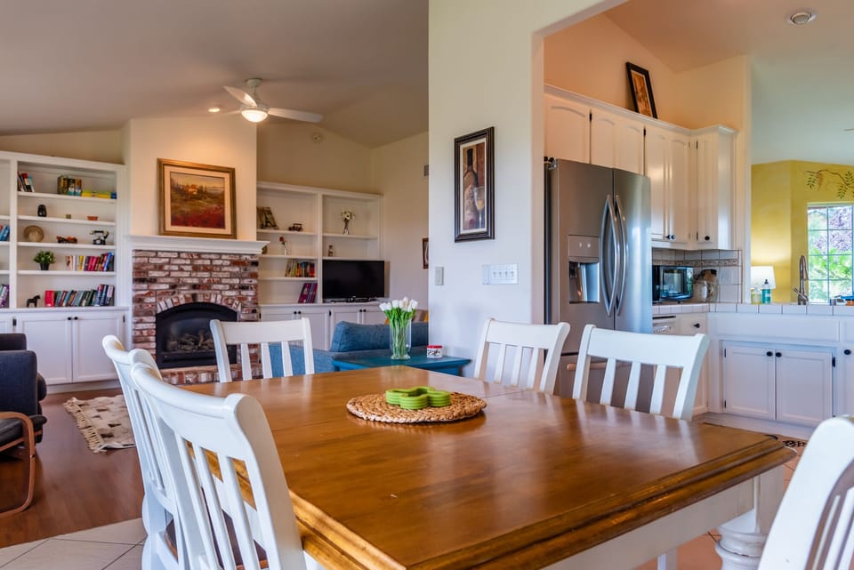 A dining table opens to the fireplace-centered living area and kitchen.