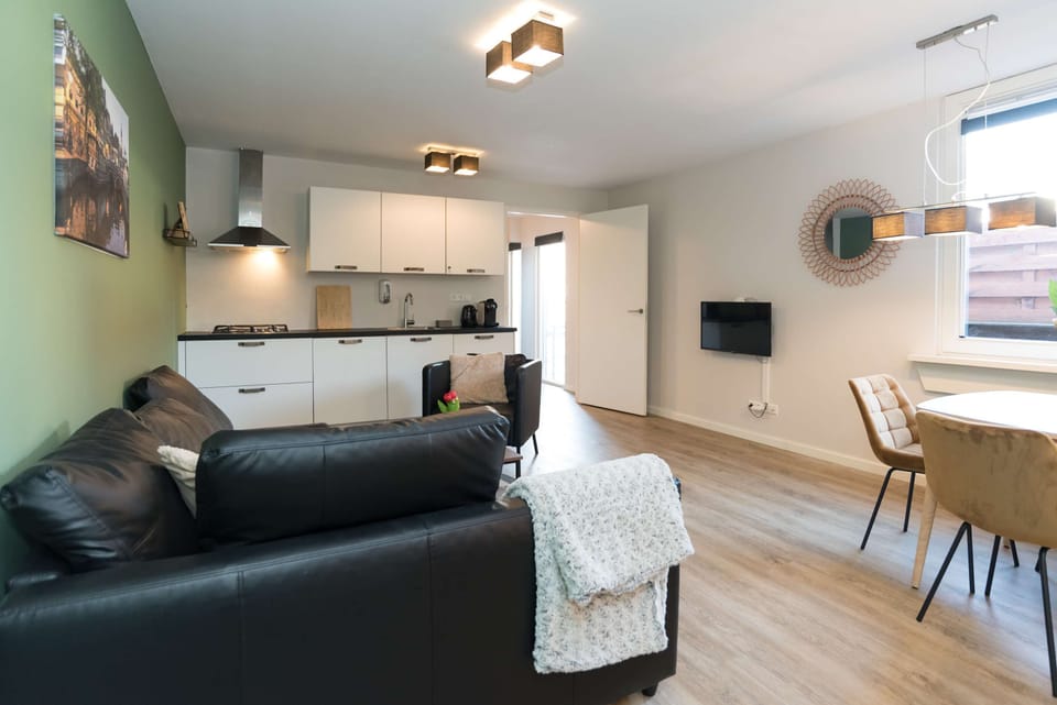 Bright and spacious living area with modern decor, comfortable seating, and dining table – ideal for relaxing after a day in Alkmaar.