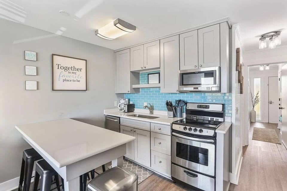 Kitchen with stainless steel appliances and prep island with seating. Sea Cabin 208A, Isle of Palms, SC | IOP Escapes