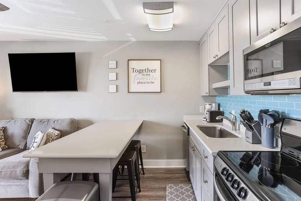 Kitchen with stainless steel appliances and a prep island with seating. Sea Cabin 208A, Isle of Palms, SC | IOP Escapes