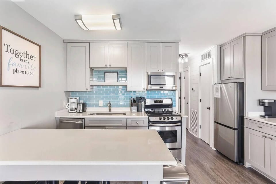 Kitchen with stainless steel appliances and prep island with seating. Sea Cabin 208A, Isle of Palms, SC | IOP Escapes