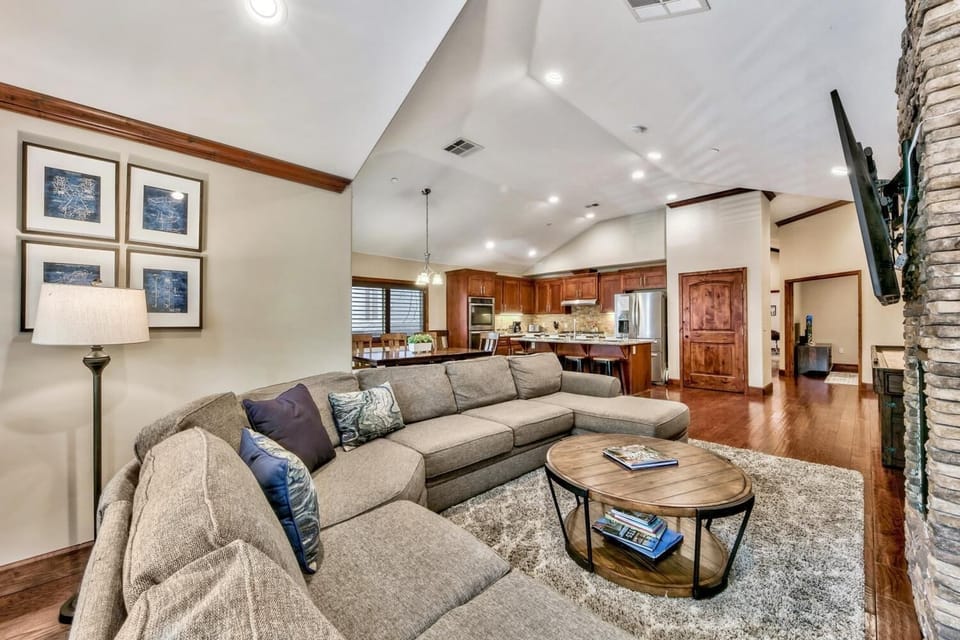 Sink into plush sectional seating in your open-concept living space, where warm wood tones and soaring ceilings create an inviting atmosphere.