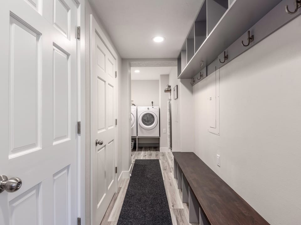 Garage Entryway with private laundry closet, convenient bench, and hooks for hanging equipment