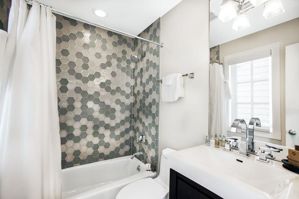The sparkling bathroom holds a tub/shower combination.