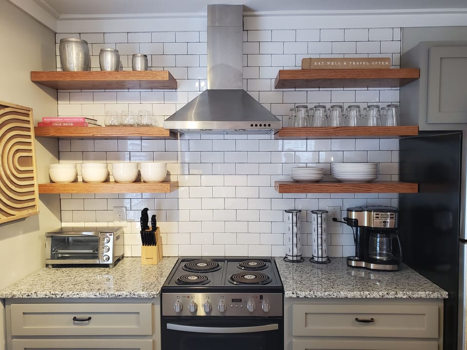 Kitchen has open shelving, drip coffee maker, toaster oven, & knife block