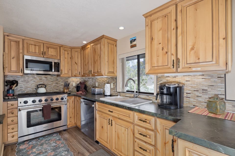 Your fully-equipped kitchen features warm wood cabinetry, granite countertops, and stainless steel appliances—perfect for preparing home-cooked meals during your stay.