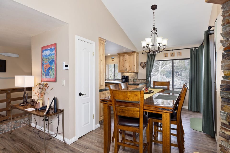 Gather around the inviting dining table, where warm wood tones and natural light through expansive windows create the perfect setting for your morning coffee or evening meals with loved ones.