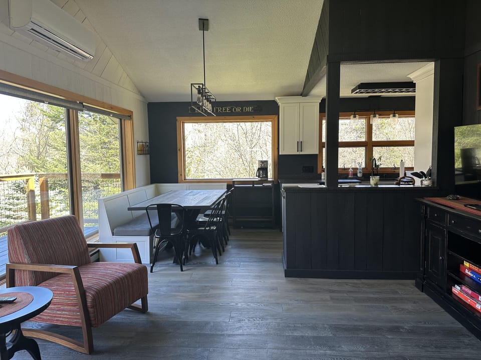 Dining area with built-in bench and large window overlooking trees.