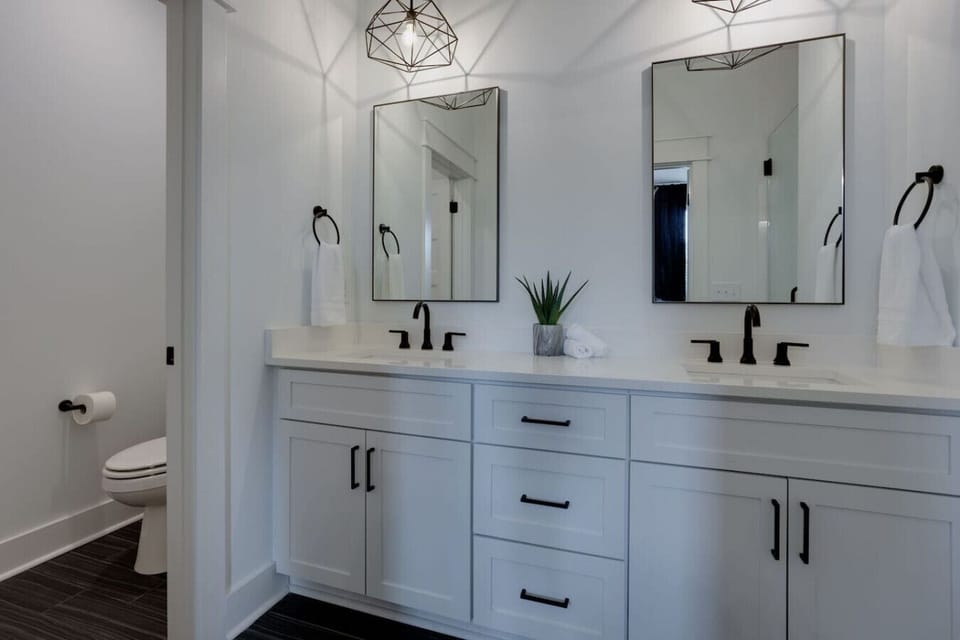 Spacious bathroom with double vanity, white cabinetry, and black hardware