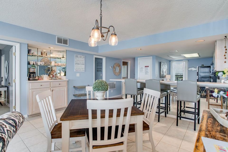 Dining area with chandelier and open kitchen at Wind Drift Orange Beach