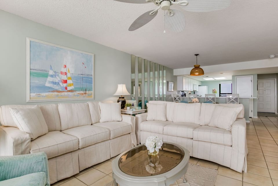 Living area with white furniture and Gulf-front windows at Wind Drift Orange Beach