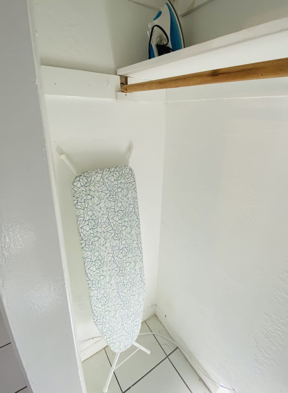 Bedroom closet with hangers, laundry basket, iron and iron table