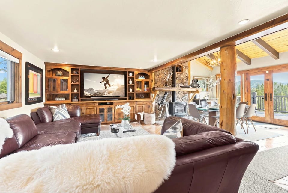 Spacious family room with luxurious sectional sofa, cozy indoor gas fireplace, tall windows, and a large flat-screen TV