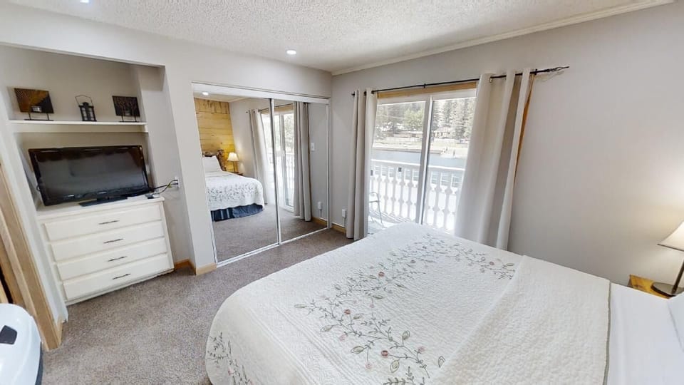Your serene bedroom features a plush bed, built-in entertainment niche, mirrored closet, and balcony access with lovely outdoor views—perfect for peaceful mountain mornings.