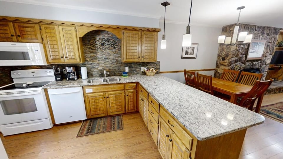 Spacious kitchen with granite countertops and fully-equipped appliances flows into a welcoming dining area—perfect for preparing family meals and gathering together during your mountain retreat.
