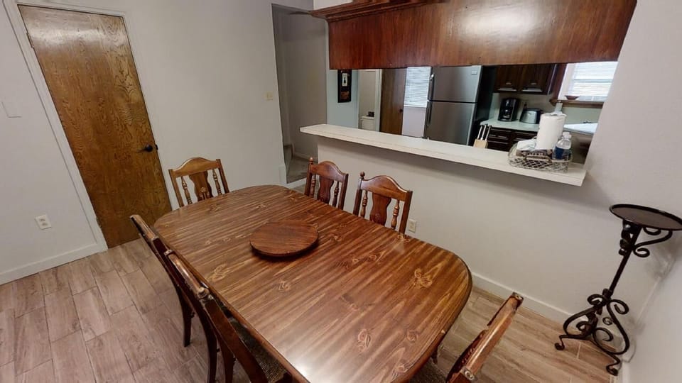 Your dining space flows seamlessly into a well-equipped kitchen, perfect for preparing meals and gathering around the warm wood table with family and friends.