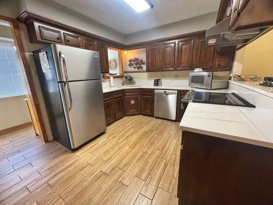 Your fully equipped kitchen awaits with stainless steel appliances, rich wood cabinetry, and ample counter space—perfect for whipping up morning coffee or a home-cooked meal during your stay.