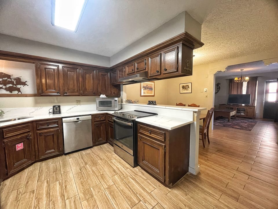 Picture yourself preparing meals in this fully-equipped kitchen with rich wood cabinetry, stainless steel appliances, and a convenient island. Natural light from the skylight brightens your mornings while you enjoy the open layout.