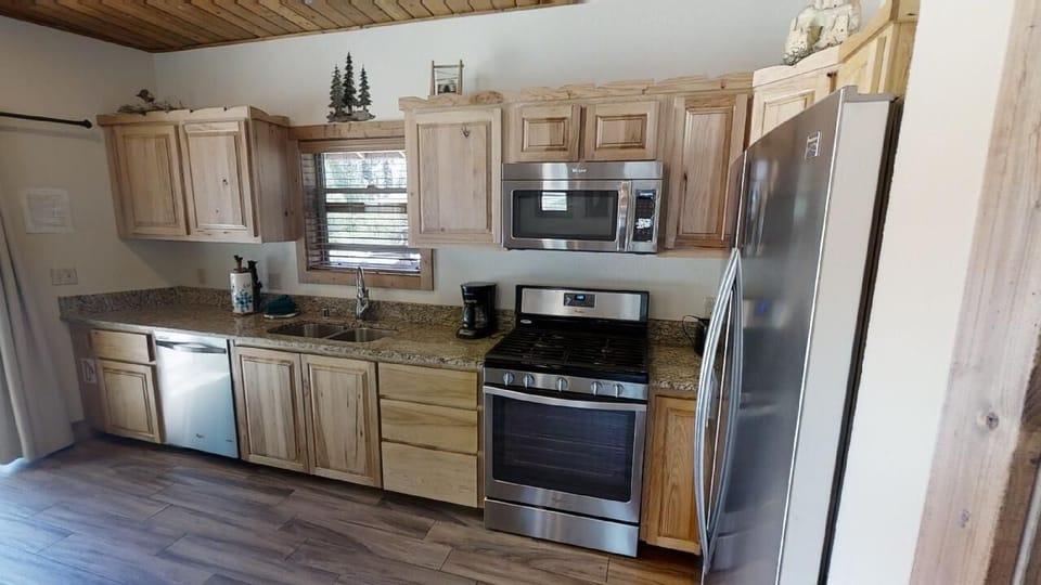 Your fully equipped kitchen features stainless steel appliances, granite countertops, and warm wood cabinetry—perfect for preparing meals together during your mountain getaway.