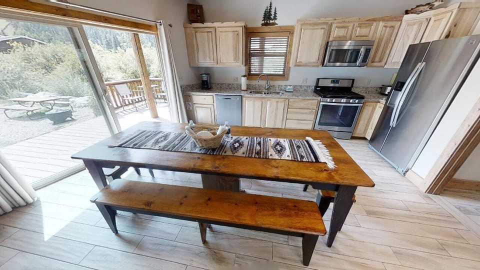 Step into your well-appointed mountain retreat with a full kitchen featuring stainless steel appliances, granite counters, and charming light wood cabinetry. The open dining area flows seamlessly to your private deck overlooking peaceful forest views.