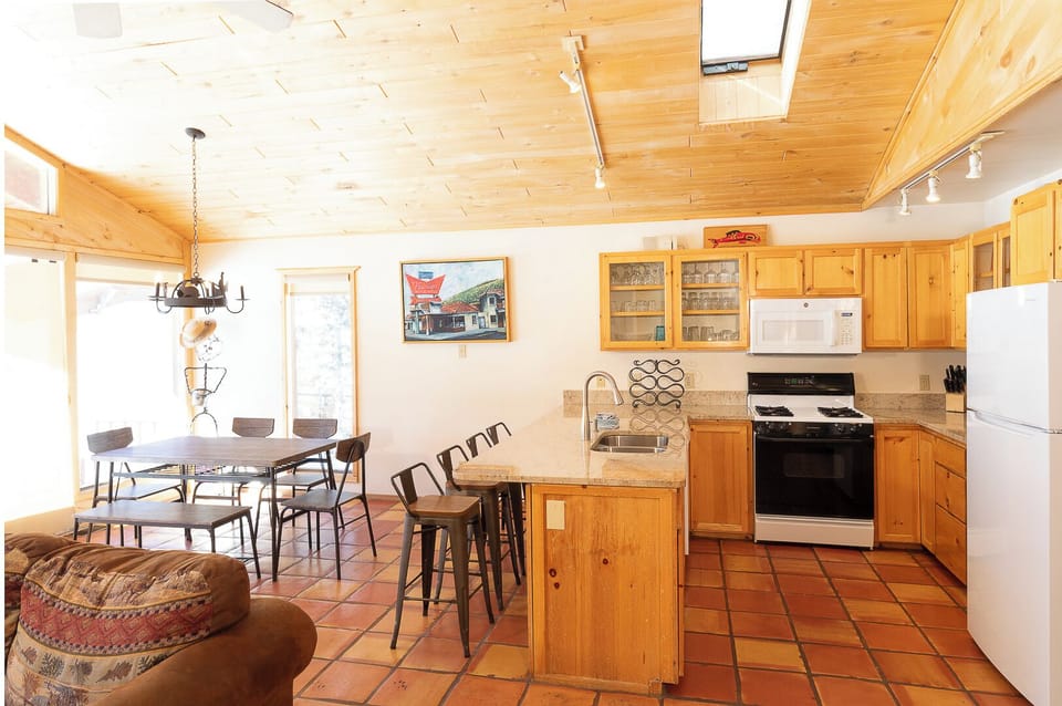 Gather around the handcrafted wooden island for morning coffee or unwind in the spacious open-plan living area, where warm pine accents and abundant natural light create your home away from home.