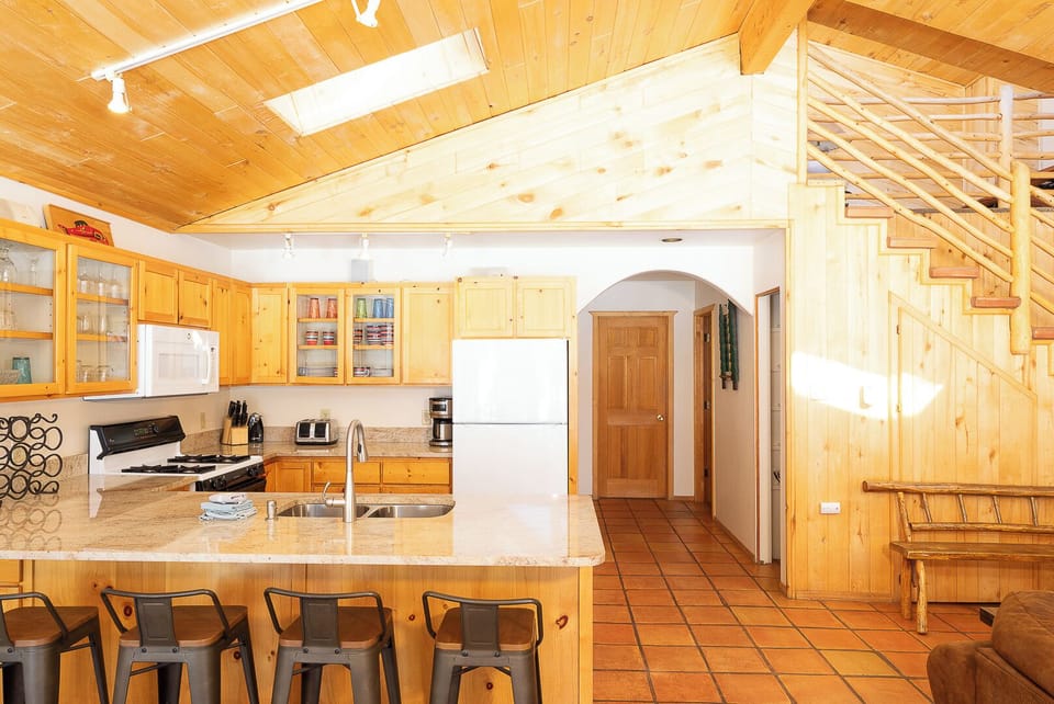 Step into your open-concept retreat with vaulted wood ceilings, a fully-equipped kitchen with granite counters, and warm terracotta floors that invite you to cook, gather, and unwind.