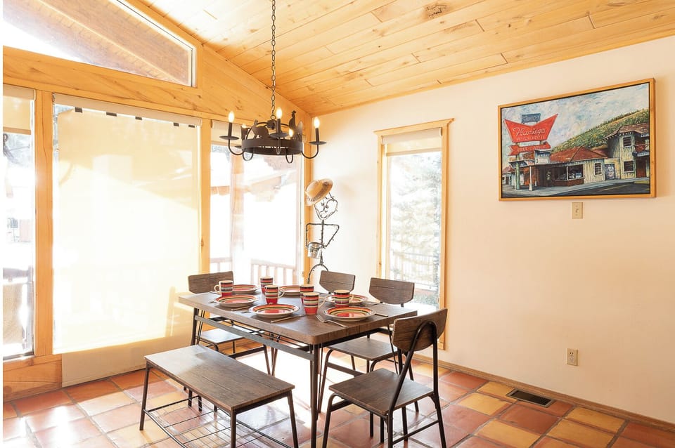Gather around this sunlit dining table where warm wood ceilings and cheerful artwork set the scene for your memorable meals together.