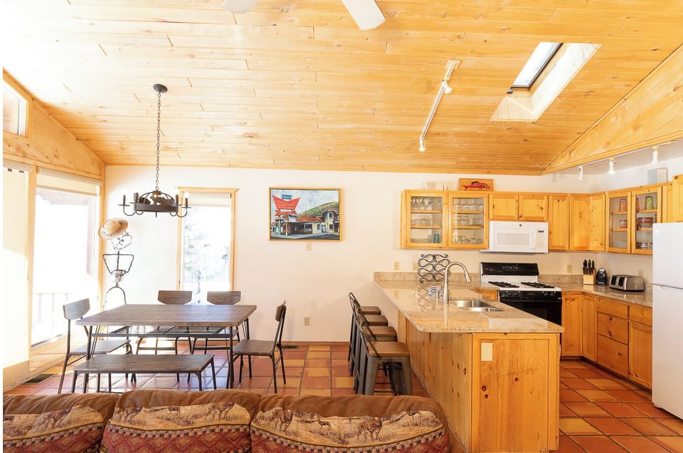 You'll love the bright, airy feel of this open living space with vaulted wood ceilings, skylights flooding warmth, and a well-equipped kitchen perfect for home-cooked meals.