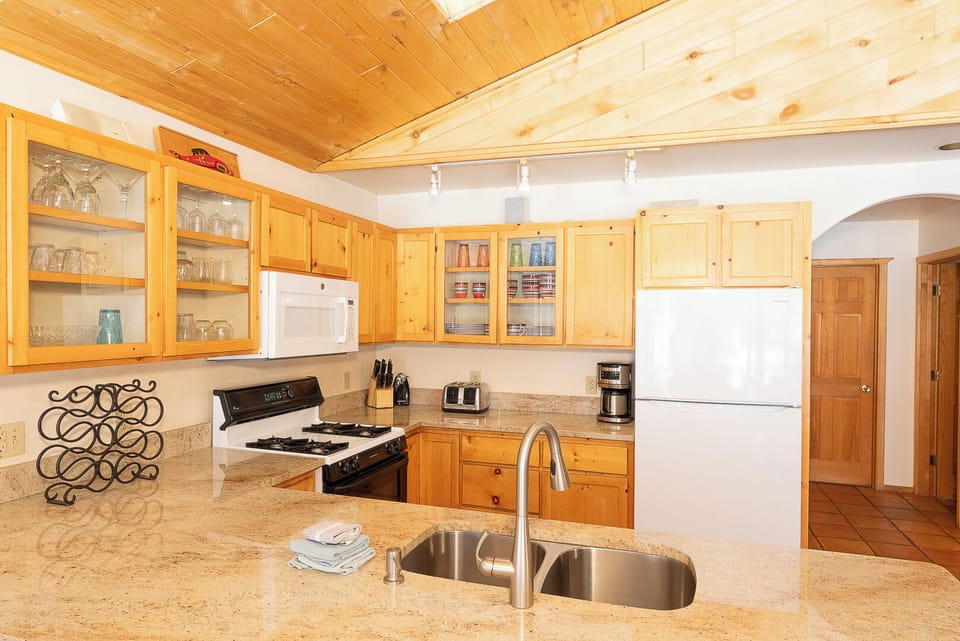 A fully-equipped kitchen with warm pine cabinetry and granite countertops, ready for you to prepare your favorite meals during your stay.