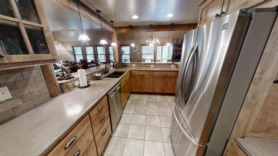 Your gourmet kitchen awaits with stainless steel appliances, granite counters, and warm wood cabinetry—perfect for whipping up memorable meals while gazing out at the scenic views beyond.