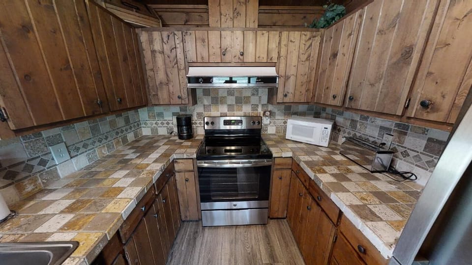 Your fully equipped kitchen awaits with rustic wood charm, tile backsplash, and modern appliances—everything you need to prepare meals while enjoying the cozy cabin atmosphere.