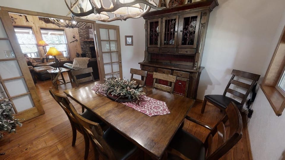 Gather around this handsome dining table beneath the rustic antler chandelier, where warm wood tones and cozy touches set the scene for memorable meals with your group.