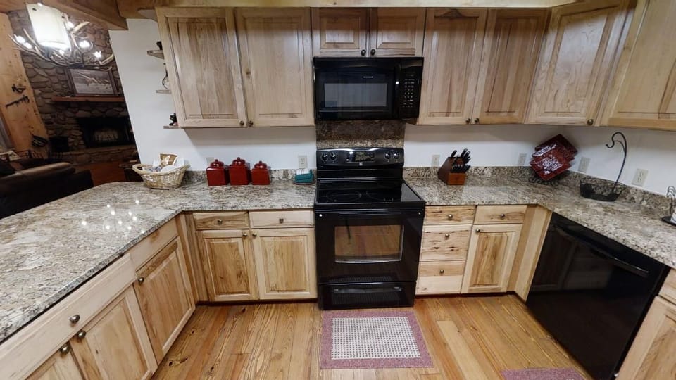 The fully equipped kitchen features granite countertops, modern black appliances, and plenty of storage space for preparing your favorite mountain meals together.