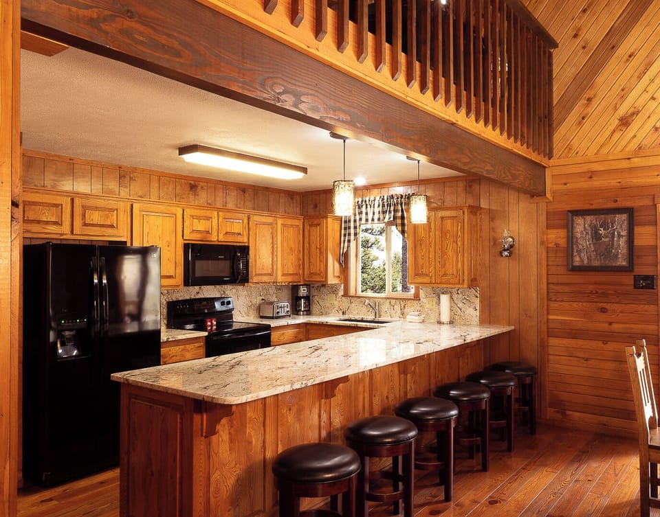Gather around this spacious kitchen island with granite countertops, where you can prepare meals with modern appliances while enjoying the warm wood cabin ambiance and lofted ceilings above.