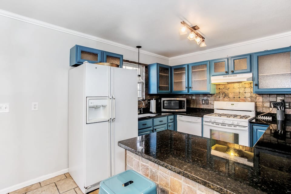 well stocked kitchen with granite, gas stove and coffee maker 