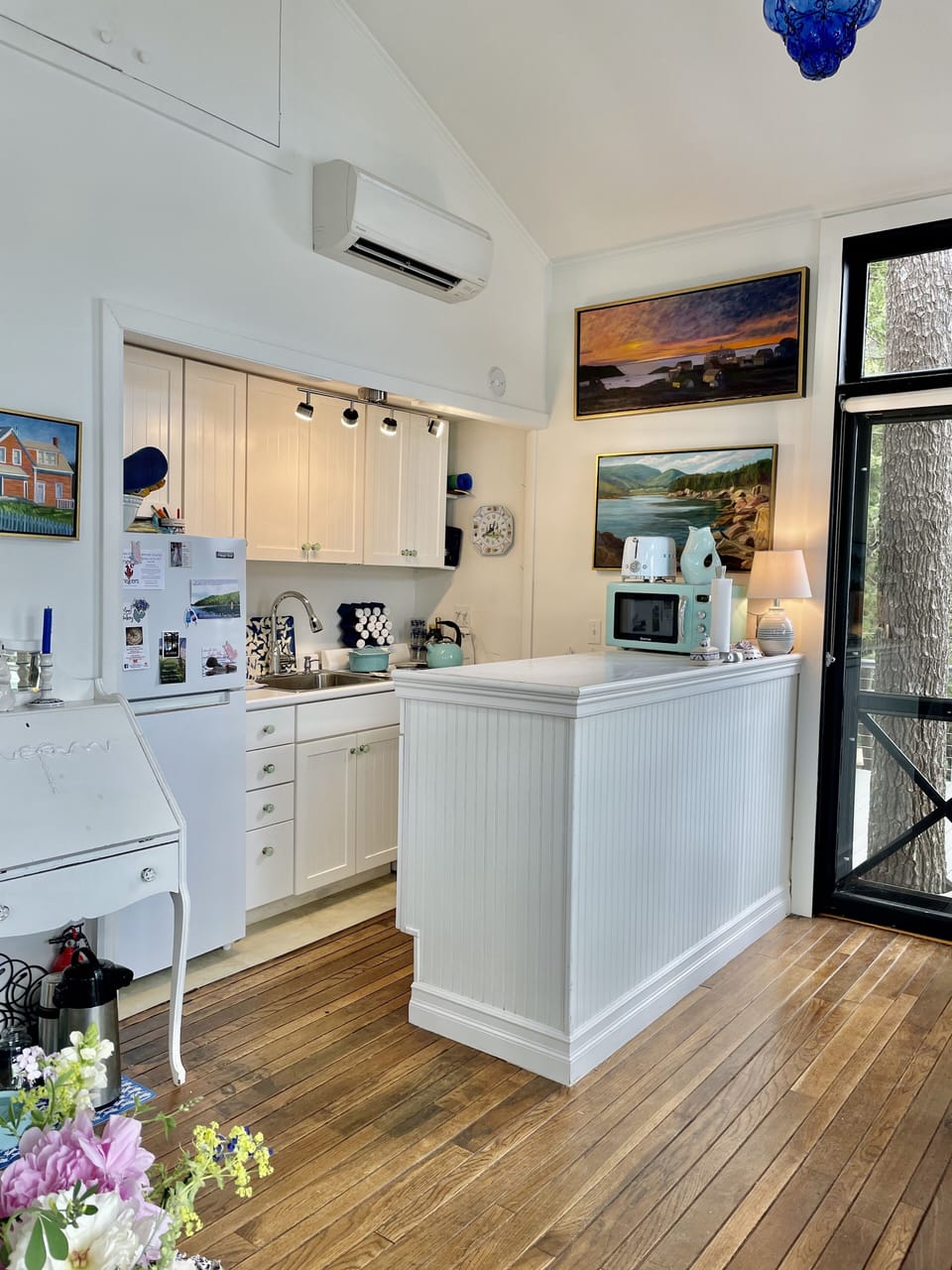 View of Kitchen and Island with door to side deck. Heatpump above kitchen.