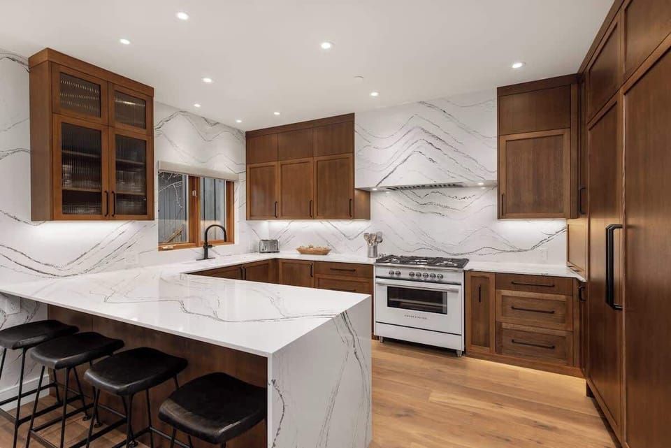 - Chef’s kitchen with marble waterfall countertops and backsplash  
- Custom wood cabinetry and gas range for gourmet cooking  
- Breakfast bar with stools ideal for morning coffee moments 