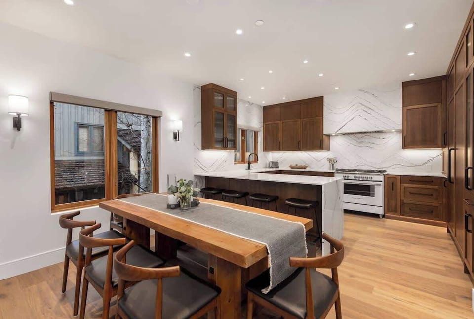 - Open concept kitchen and dining with sleek marble backsplash  
- Wooden cabinetry and high-end appliances for chef-style cooking  
- Long dining table ideal for shared mountain meals  