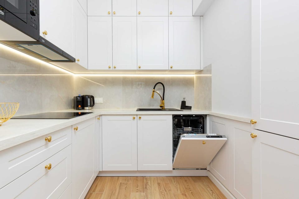 A fully equipped kitchen with sleek white cabinetry, modern appliances, and ample lighting.
