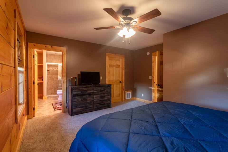 Rest easy in this cozy bedroom at Firefly Cabin, complete with a ceiling fan and a private en-suite bath just steps away.